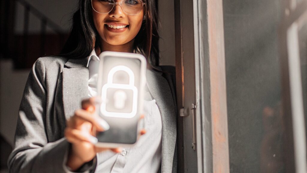 Mujer latina sonriendo con alivio y confianza mientras sostiene su celular, con un ícono de un candado brillante sobre la pantalla.